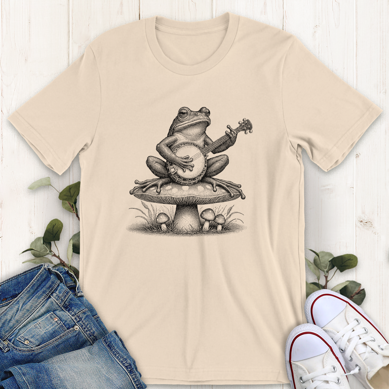 Soft cream Banjo frog on a mushroom graphic t-shirt by Thistle and Brass